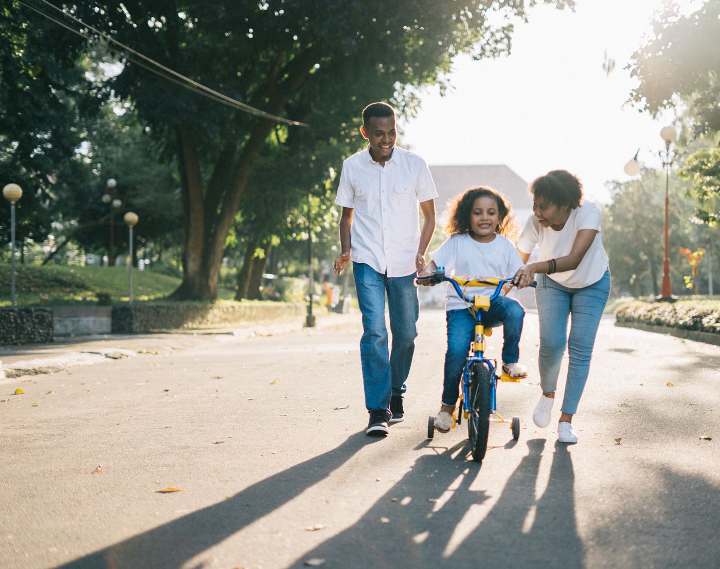 Pais a ensinar a filha a andar de bicicleta